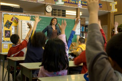 Elementary classroom setting.  Focus on teacher and chalkboard.